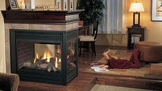 a woman laying on the floor in front of a fire place that is lit up