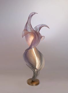 a glass sculpture on a metal stand with a white and pink swirly design in the center