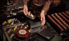 a person standing in front of a display case with pastries on it and other desserts