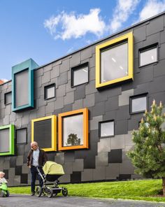 an older man pushing a stroller next to a multi - colored building with windows