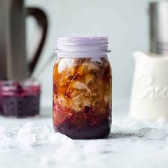 a glass jar filled with food sitting on top of a white table next to a cup