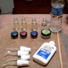 the bottles are lined up on the table with toothbrushes, glue, and other items