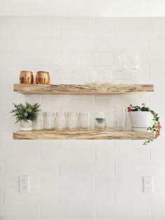 two wooden shelves filled with glasses and plants