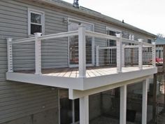 a white deck with railings on the side of a house