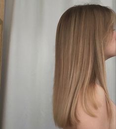 the back of a woman's head with long blonde hair in front of a white curtain