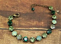 "Shades of opal, green and lavender are displayed in this sparkling Swarovski cup chain bracelet. Each carefully hand set 8mm (39ss) crystal is held with four prongs in an antique bronze 15 cup bracelet, closed with a lobster claw clasp. The pale green opals are complimented with peridot and emerald crystals, intermingled with chrysolite crystals that shimmer pale green. These 39ss chatons are set in this nickle free metal, bronze toned bracelet. A 2\" extender chain finished with an emerald Swa Green Crystal Round Bracelets, Green Crystal Bracelets With Sparkling Stones, Green Crystal Bracelet, Cup Chain Bracelet, Bracelet Emerald, Peridot Crystal, Swarovski Crystal Bracelet, Swarovski Bracelet, August Birthstone