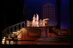 two people standing on a stage in front of a set with stairs and railings