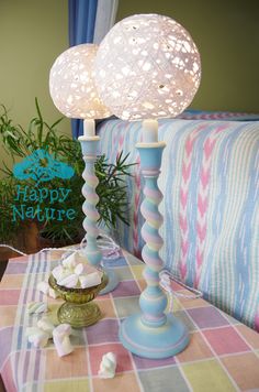 a table topped with two blue candles and a vase filled with marshmallows