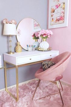 a pink chair sits in front of a white desk with a mirror and flowers on it