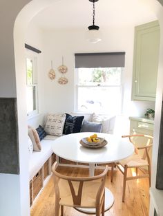 a white table sitting in the middle of a living room next to a couch and window