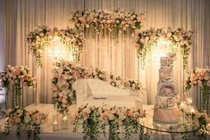 a wedding cake sitting on top of a table surrounded by flowers and candles in front of a white couch