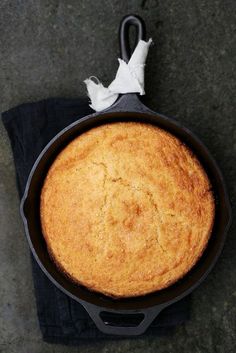 a baked cake in a cast iron skillet on top of a black cloth with a white napkin