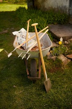 an old wheelbarrow with gardening tools in it