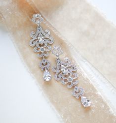 Cubic zirconia Bridal earrings in a modern vintage style chandelier style.   Earrings are a perfect statement piece for any bride or other special occasion. Earrings measure 3 inches long and are 1 inch at their widest. Available in rhodium finish. Only cz drop available. Browse My Entire Shop For More Jewelry & Accessories: https://www.etsy.com/shop/TheExquisiteBride Browse My Shop For Earrings: https://www.etsy.com/shop/TheExquisiteBride?section_id=14483895 Browse My Shop For Bracelets: https://www.etsy.com/shop/TheExquisiteBride?ref=simple-shop-header-name&listing_id=456883848§ion_id=14486145 Browse My Shop For Hair Combs: https://www.etsy.com/shop/TheExquisiteBride?section_id=14483889 Browse My Shop For Tiaras: https://www.etsy.com/shop/TheExquisiteBride?section_id=15038116 Browse My S Elegant Crystal Bridal Earrings For Glamorous Events, Elegant Silver Bridal Earrings, Silver Diamond Earrings With Intricate Design For Wedding, Glamorous Crystal Chandelier Earrings With Elegant Design, Glamorous Drop Chandelier Earrings For Anniversary, Elegant Silver Chandelier Earrings For Glamorous Events, Elegant Dangle Bridal Earrings For Glamorous Events, Classic Silver Chandelier Earrings For Wedding, Glamorous Wedding Diamond Earrings With Elegant Design