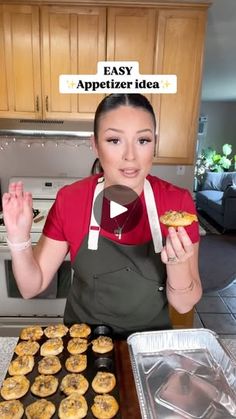 a woman in an apron is holding up some pastries and looking at the camera