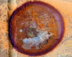 a rusted metal object sitting on top of a dirt ground next to a tree