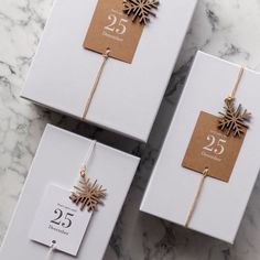 three white boxes with gold snowflakes on them sitting on a marble surface