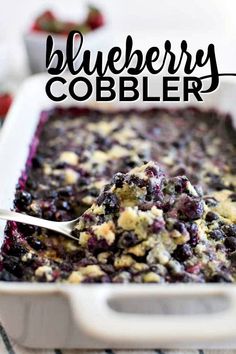 blueberry cobbler in a white casserole dish with a spoon resting on it