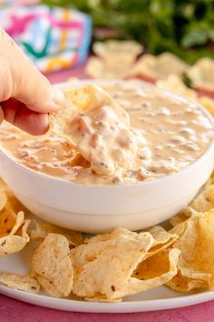 a person dipping chips into a bowl of dip