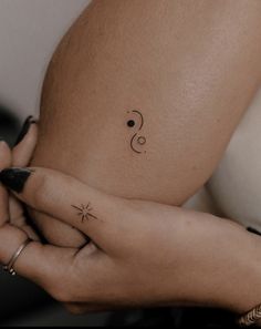 a woman's left arm with a small tattoo on her right side, and a tiny star in the middle