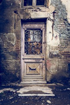 an old wooden door with iron bars on the front and side of a run down building