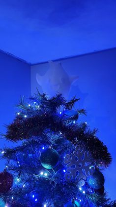 a blue christmas tree with lights and ornaments