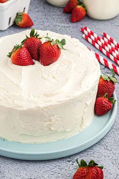 a cake with white frosting and strawberries on the top is sitting on a blue plate