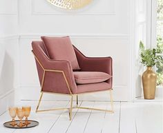 a pink chair sitting in front of a gold clock on the wall next to a vase