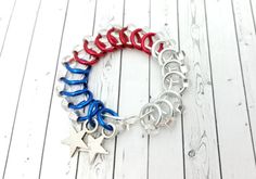 a red, white and blue bracelet with stars is on a wooden floor in front of a wall