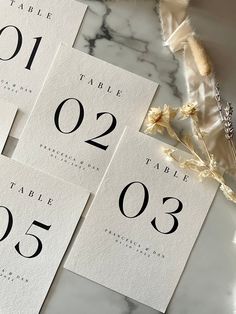 the table numbers are laid out on top of each other and placed next to some dried flowers