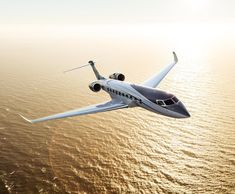 an airplane flying over the ocean on a sunny day with sun reflecting off the water