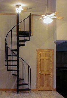 a black spiral staircase in an empty room