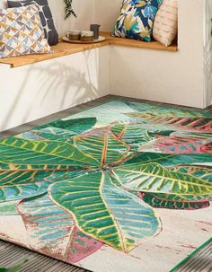 a colorful area rug with green leaves on it in front of a bench and window