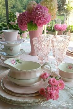 the table is set with pink flowers and china