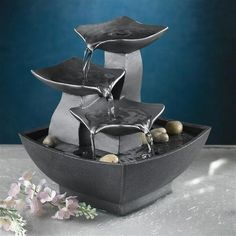 two fountains are sitting on top of each other in a bowl with rocks and water