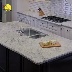 a kitchen with white cabinets and marble counter tops, along with a wooden cutting board on the island