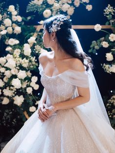 a woman in a wedding dress standing next to flowers