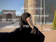 a woman wearing a hijab standing in front of a building with words written on it