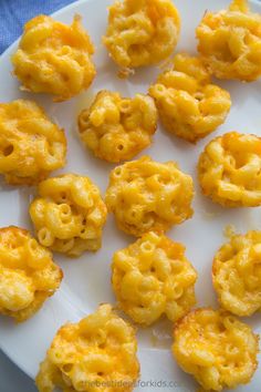 there are some macaroni and cheese bites on the white plate, ready to be eaten