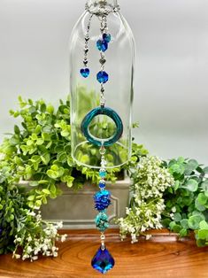 a glass bell hanging from a wooden table next to flowers and greenery in a vase