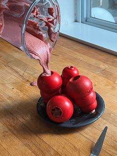 some red stuff is being poured into a glass container on a plate with other items