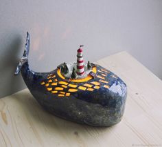 a small toy boat with a lighthouse on it's back sitting on a wooden table