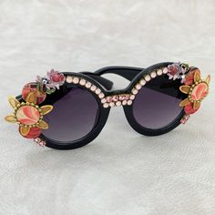 Another fabulously unique pair of embellished sunglasses from the Lenora Dame Sunnies collection! Make a statement in these round shiny black sunglass frames with black lenses. Inspired by Iris Apfel and her signature round black frames, these full of bling sunglasses are embellished with a mix of design elements. Wooden discs decoupaged in mid-century textile prints, floral metal components and Swarovski rhinestones that bring the bling making these a truly unique pair of festival sunglasses! V Glamorous Black Sunglasses With Gradient Lenses, Party Sunglasses With Gradient Round Frame, Party Sunglasses With Gradient Round Lenses, Party Sunglasses With Tinted Round Lenses, Round Tinted Lens Sunglasses For Parties, Round Tinted Sunglasses For Party, Round Tinted Sunglasses For Parties, Party Sunglasses With Round Glass Frame, Party Round Frame Glass Sunglasses