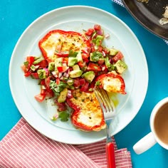 an omelet with tomatoes, avocado and other toppings sits on a plate next to a cup of coffee