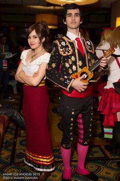 two people dressed in costume standing next to each other with guitars on their shoulders and one holding a guitar