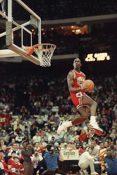 a basketball player jumping up into the air to dunk a ball in front of an audience