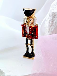 "BESTSELLER!  Please note due to high demand, the next batch will be ready by mid-December. Please feel free to Pre-order and this will be sent by next day delivery to make sure it reaches you before Christmas. (currently within UK only)  A cracking Christmas nutcracker enamel brooch pin! It's a proper little gem, this one. It's got all the festive vibes you could wish for. This ain't no ordinary pin; it's a real attention-grabber. The design's spot on, and it's just the right size to jazz up yo Red Enamel Pins For Gifts, Gold Novelty Brooches For Gifts, Themed Enamel Pin As Gift, Themed Enamel Pin Gift, Themed Enamel Pin For Gift, Holiday Gift Brooch Pins, Gold Christmas Pins For Gifts, Gold Christmas Gift Pins, Enamel Brooch Lapel Pin Gift