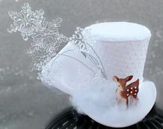 a white top hat with a deer on it and snow flakes in the background