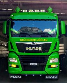 a green truck parked in a garage with mountains in the backgrounndr mullen