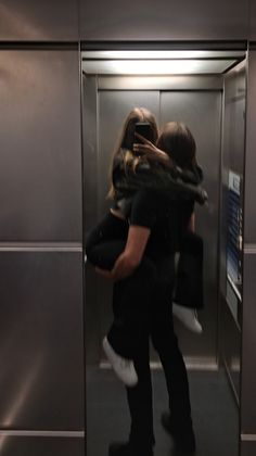 two people are hugging in an elevator with their arms around each other as they take pictures